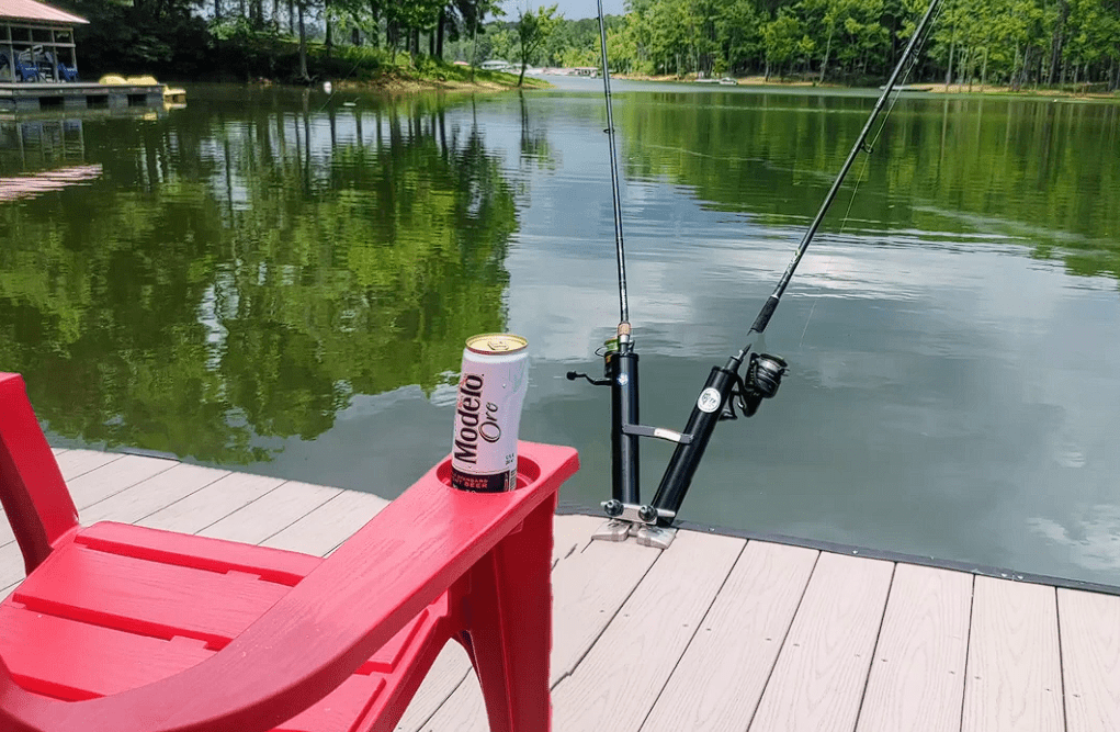 Fishing rods and a can of beer on a red chair by a lake